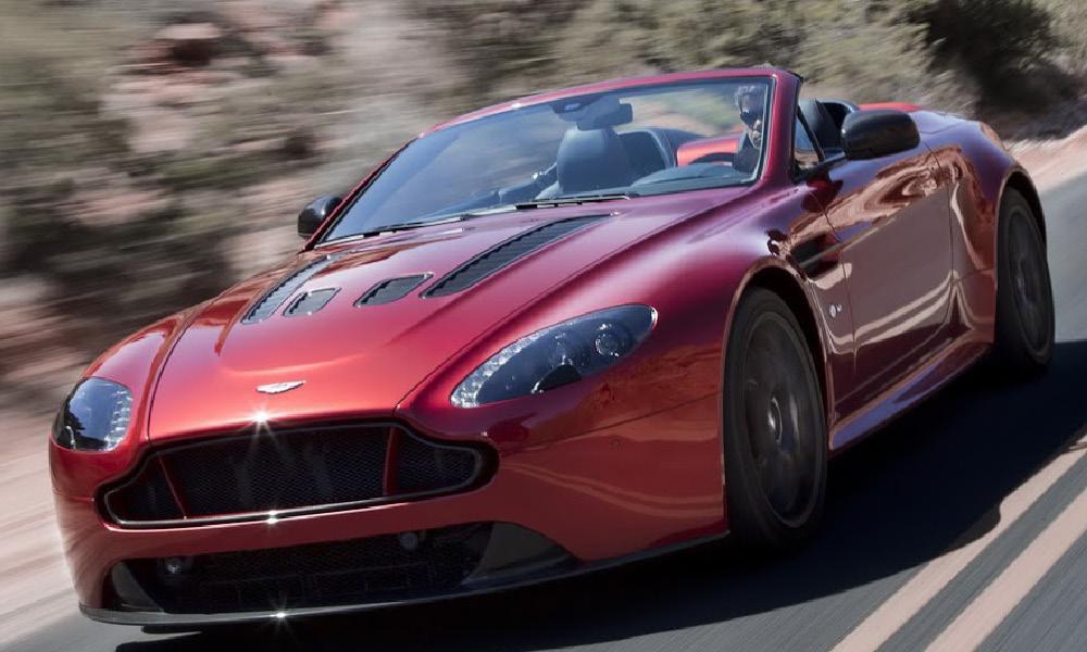 En Aston Martin Vantage S kör nedför en bergsväg. (AI text)