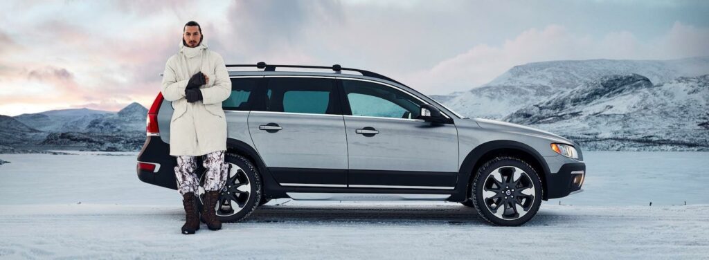 En man står bredvid en bil i snön. (AI text)