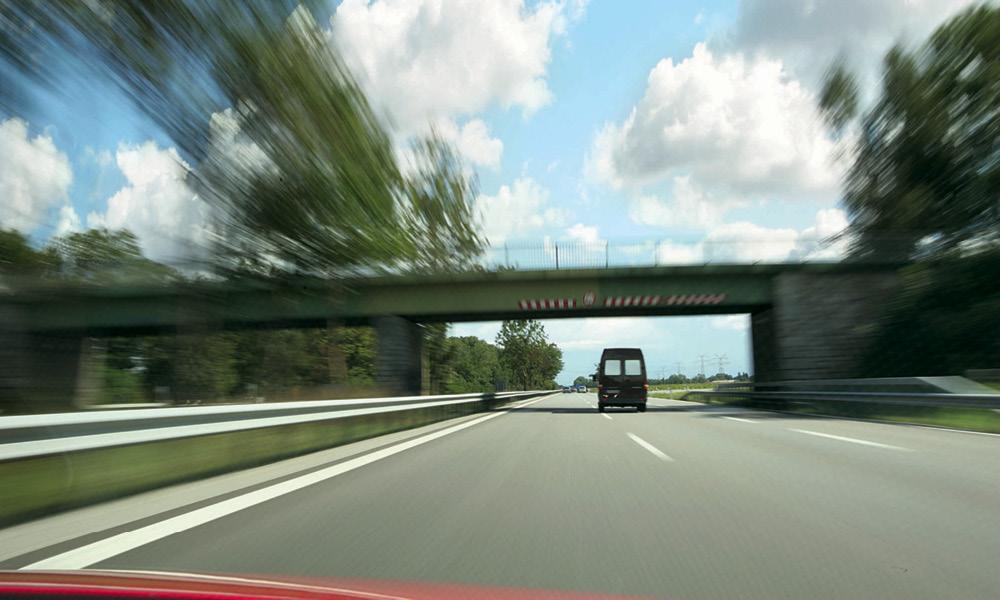 En bil kör längs en motorväg. (AI text)