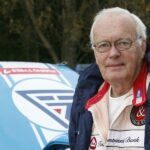 En man står bredvid en bil. (AI text)