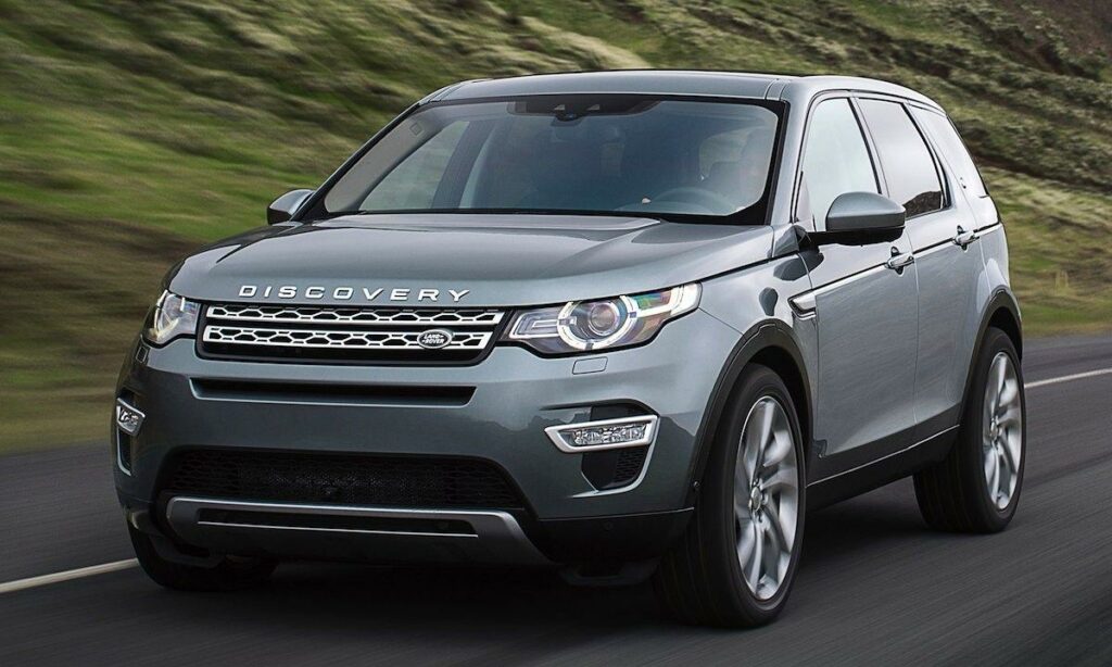 En silverfärgad Land Rover Discovery kör nedför en landsbygdsväg. (AI text)