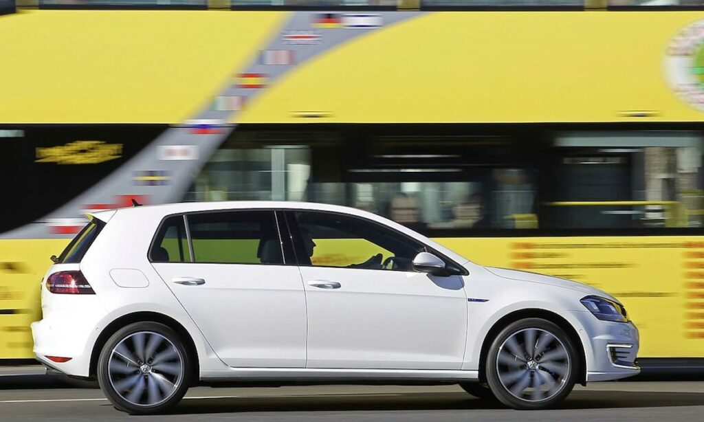 En Volkswagen Golf GTI kör förbi en buss. (AI text)