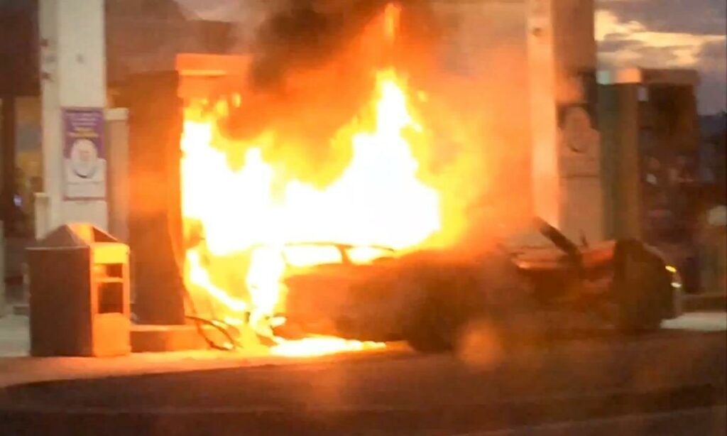 En bil brinner på en bensinstation. (AI text)