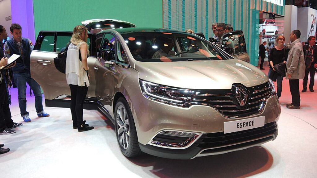 En grupp människor står omkring en bil på en bilmesse. (AI text)