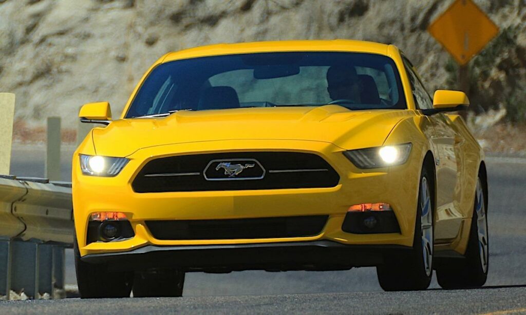 En gul Ford Mustang kör nerför en bergsväg. (AI text)
