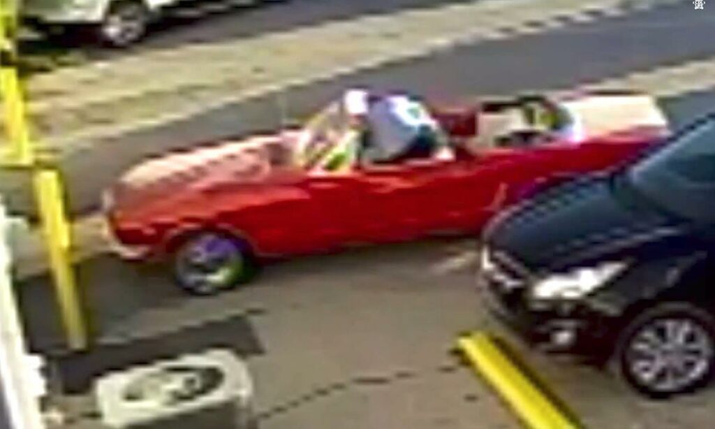 En röd cabriolet står parkerad framför en bil. (AI text)