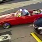 En röd cabriolet står parkerad framför en bil. (AI text)