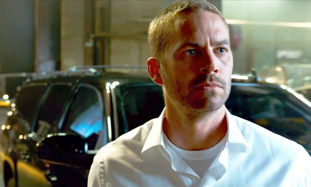 En man i ett vitt skjortan står bredvid en bil. (AI text)