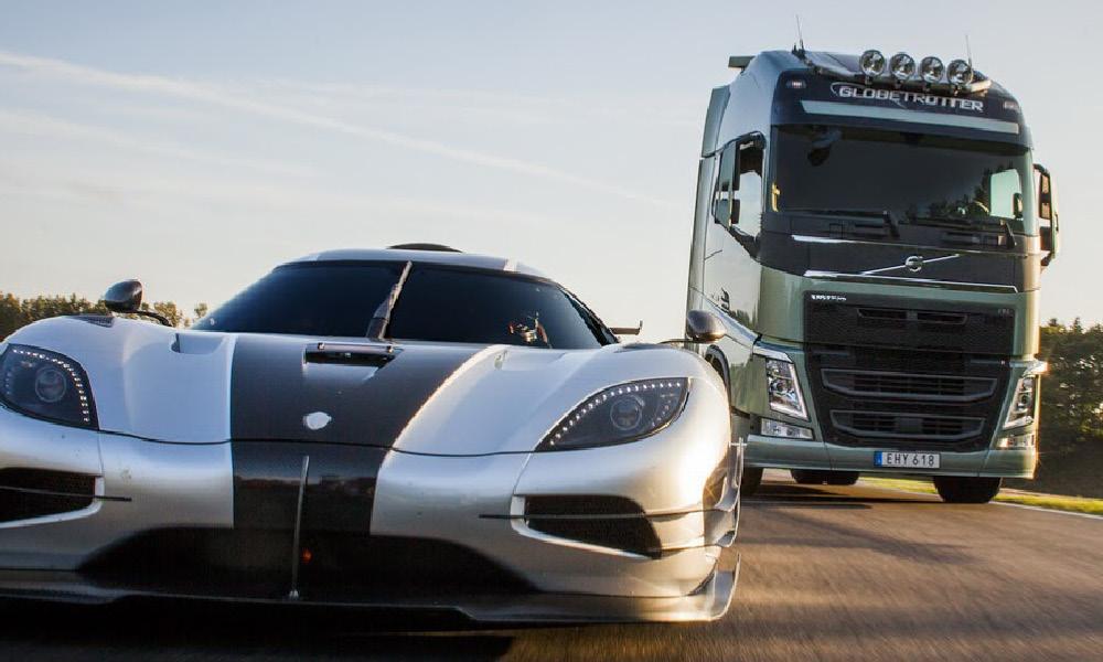 En silverfärgad Koenigsegg Jesko kör längs en väg bredvid en stor lastbil. (AI text)