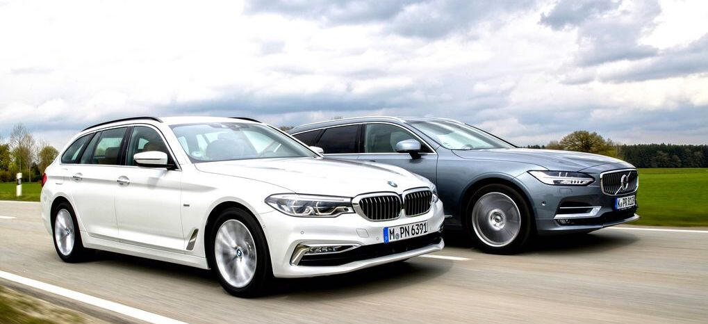 Två BMW X5 kör längs en landsväg. (AI text)