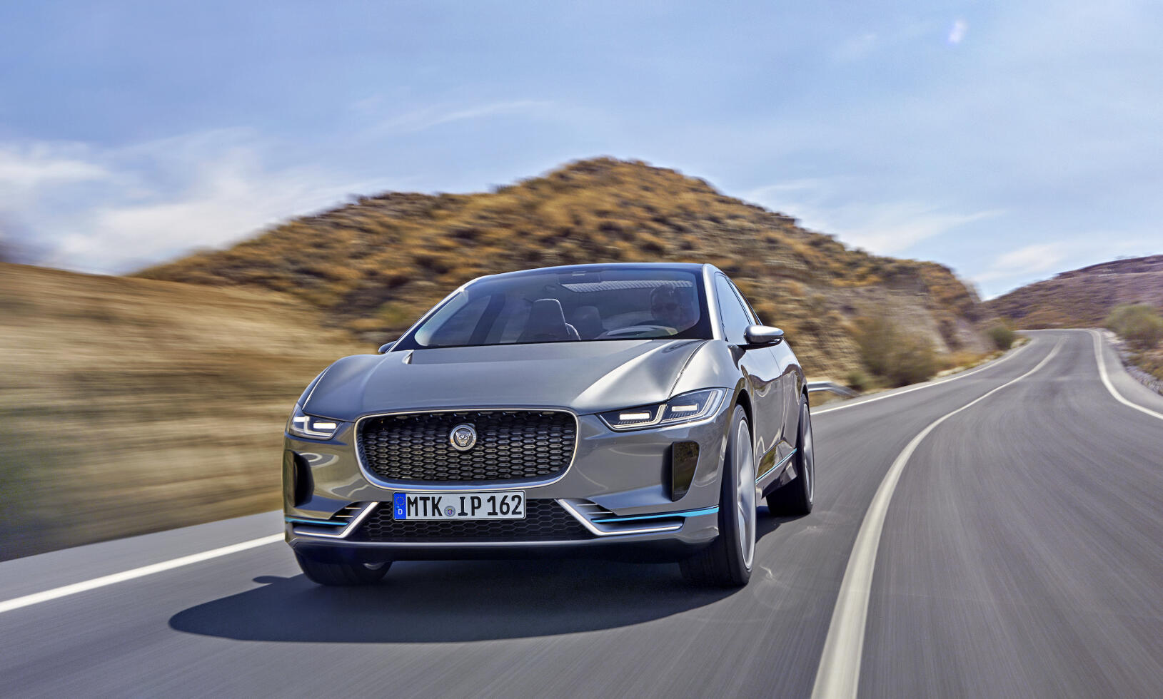 En Jaguar I PACE kör nerför en bergsväg. (AI text)
