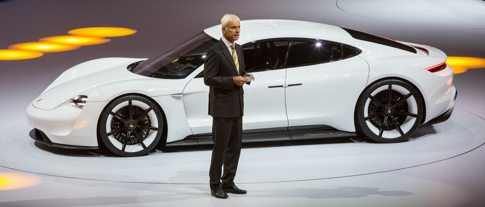 En man står bredvid en vit Porsche-bil. (AI text)