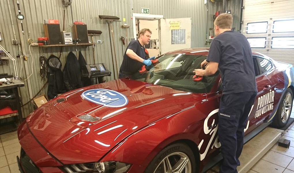 Två män arbetar på en röd sportbil. (AI text)