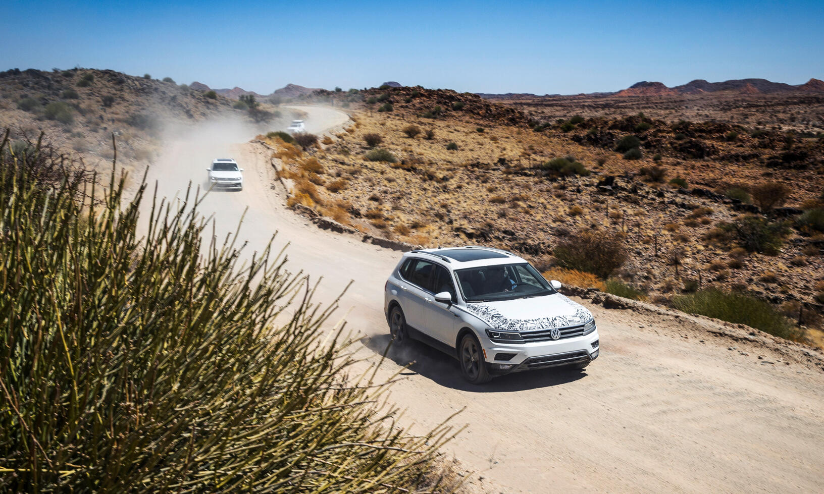 En bil kör nedför en stenig väg i öknen. (AI text)