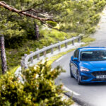 En blå Ford Fiesta st kör nerför en bergsväg. (AI text)