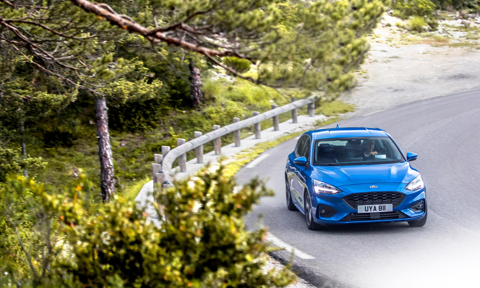 En blå Ford Fiesta st kör nerför en bergsväg. (AI text)