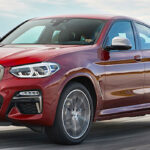 En BMW X4 kör på en väg. (AI text)