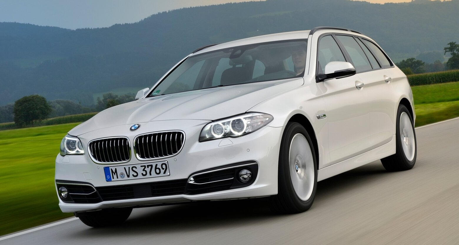 BMW 5-serie touring kör på en landsväg. (AI text)