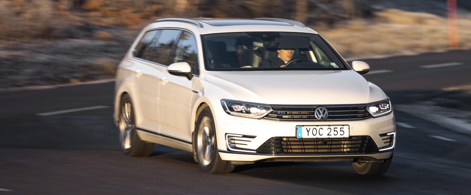 En vit Volkswagen Golf kör nerför en bergsväg. (AI text)