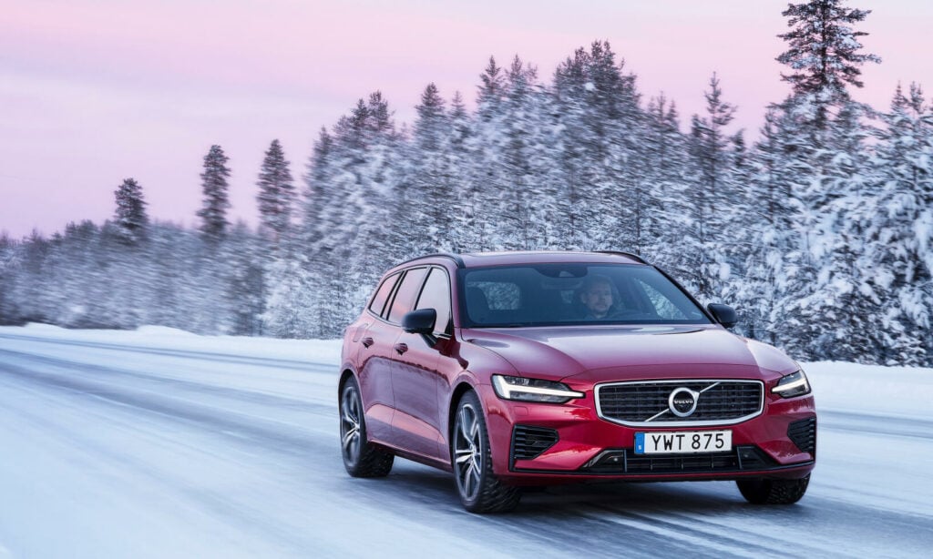 En röd Volvo V60 Cross Country kör nedför en snöig väg. (AI text)