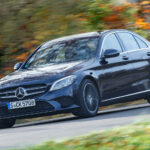 Mercedes-Benz C-klass sedan kör längs en landsväg. (AI text)