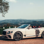 En kvinna står bredvid en Bentley Continental GT cabriolet. (AI text)