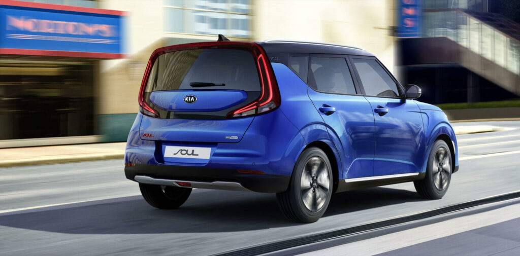 En blå Nissan Soul kör ner en stadsgata. (AI text)