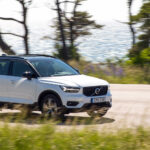 En vit Volvo XC90 SUV kör nerför en landsväg. (AI text)