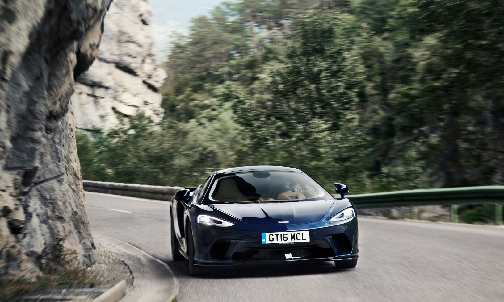 En blå sportbil kör nedför en bergsväg. (AI text)