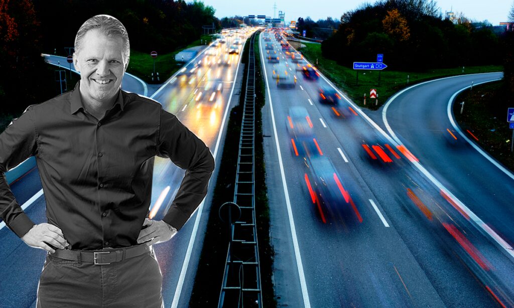 En man står på en motorväg med trafik. (AI text)