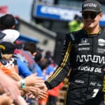 En racerförare hälsar på fans vid banan. (AI text)