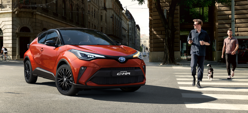 En Toyota C-HR-SUV kör nedför en stadsgata. (AI text)