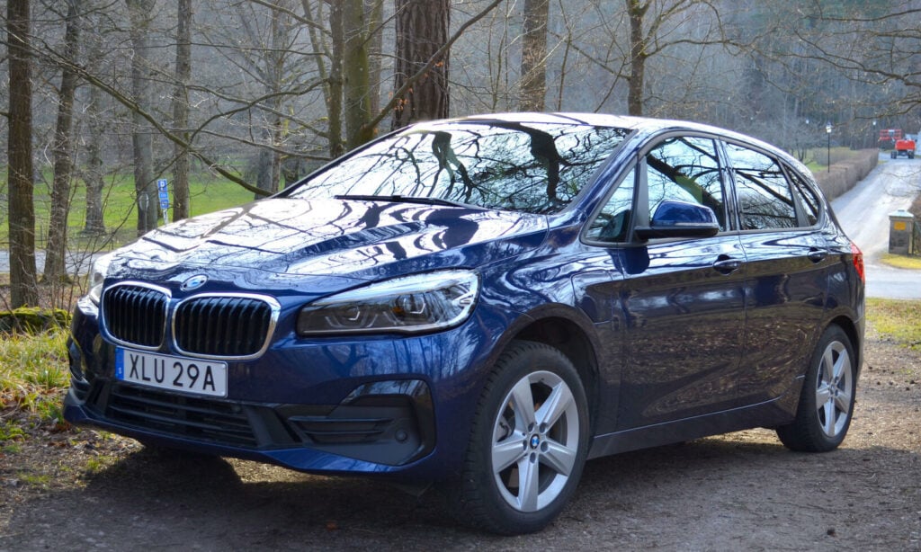 En BMW 2-serie Active Tourer parkerad i en skog. (AI text)