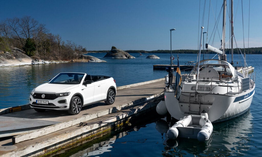 En vit bil parkerad vid en piersida. (AI text)