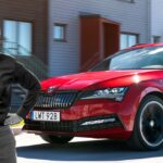 En man står bredvid en röd Skoda Polo. (AI text)