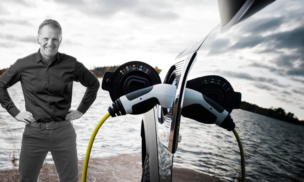 En man står bredvid en bil och laddar den. (AI text)