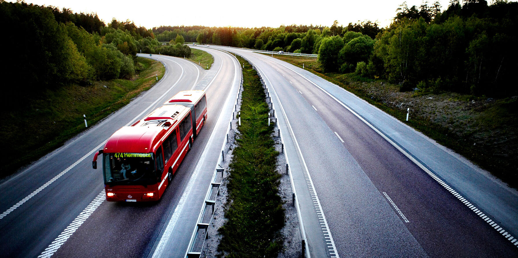 En röd buss kör längs en motorväg. (AI text)
