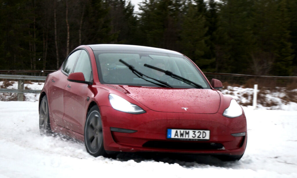 Tesla Model 3 kör i snö. (AI text)