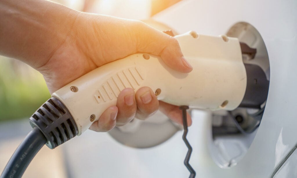 En person laddar en elbil. (AI text)