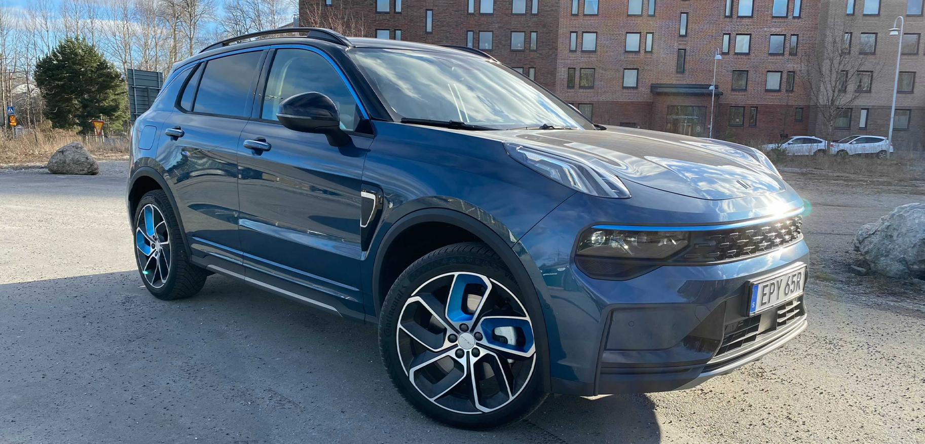 En blå SUV parkerad framför ett byggnad. (AI text)