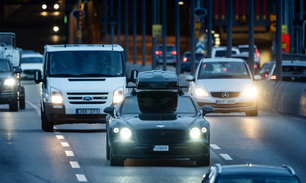 En bil körer nedför en stadsgata på natten. (AI text)