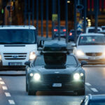 En bil körer nedför en stadsgata på natten. (AI text)