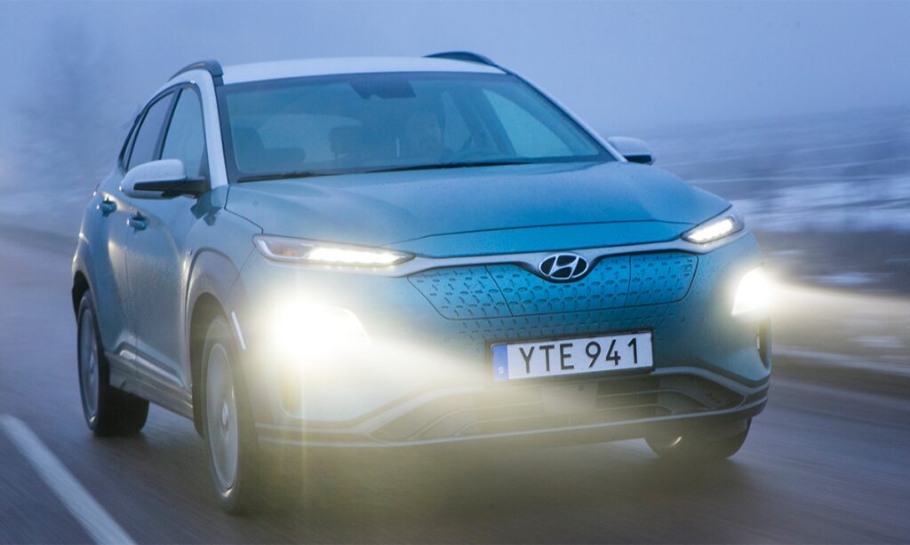 En grönglansig Hyundai Kona kör nerför en snötäckt väg. (AI text)