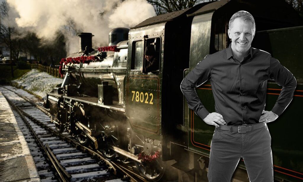 En man står bredvid en ånglokomotive. (AI text)