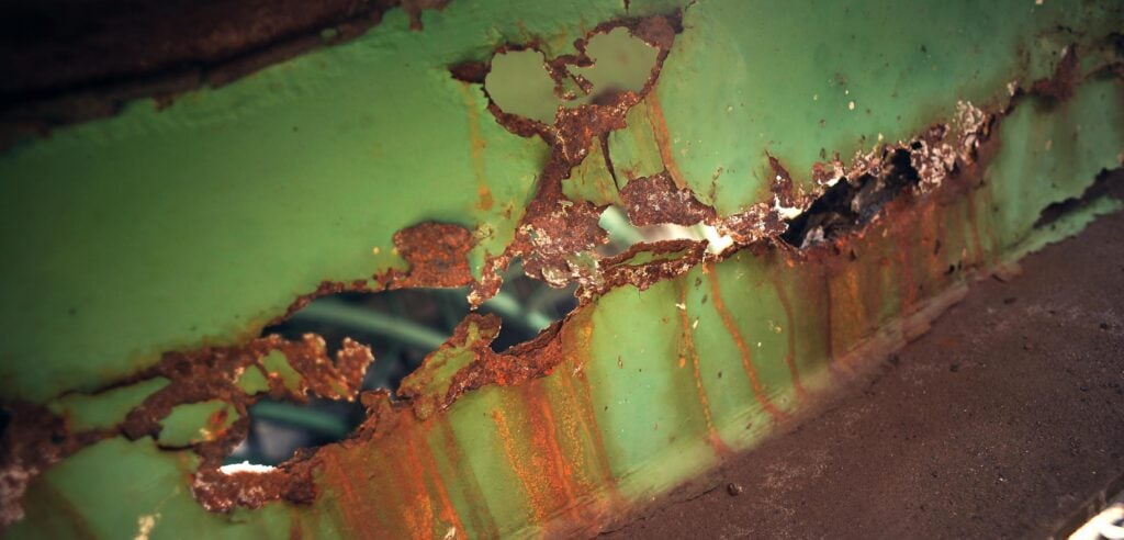 en grön bil med rödbrun rostig lackering (AI text)