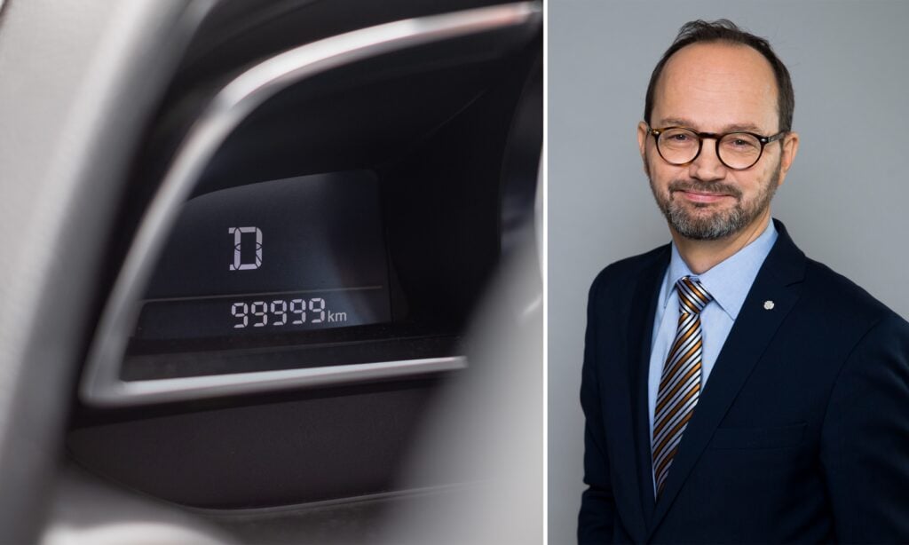 En man i kostym och slips står bredvid en bil. (AI text)