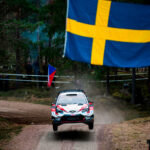 En rallybil flyger över en skog. (AI text)