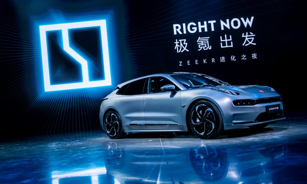 Zeekr 001. I bakgrunden det nya bilmärkets logotyp.