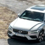 En Volvo XC90 SUV kör nerför en grusväg. (AI text)