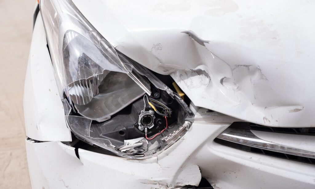 En vit bil med skadad framdel. (AI text)